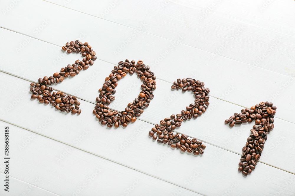 Figure 2021 made of coffee beans on white wooden background