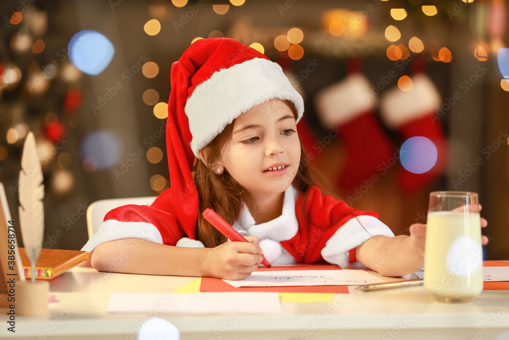 Little girl writing letter to Santa at home on Christmas eve