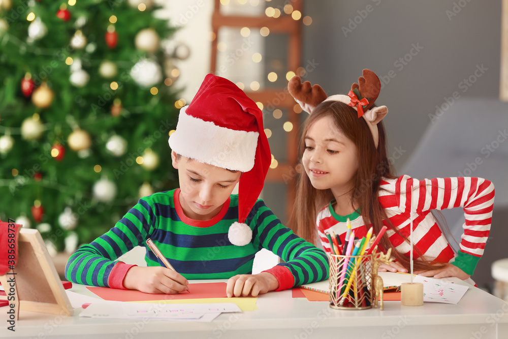 Little children writing letters to Santa at home on Christmas eve