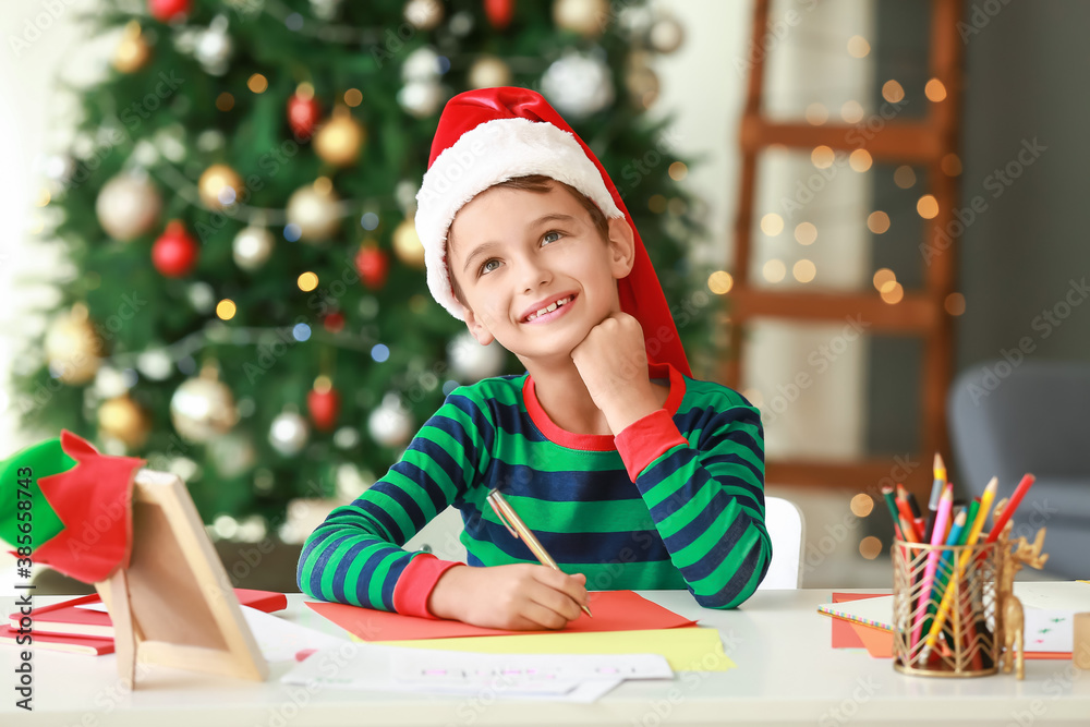 Little boy writing letter to Santa at home on Christmas eve