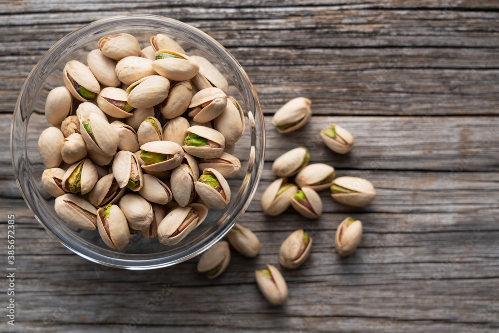 Pistachios in a bowl set against an old wooden backdrop