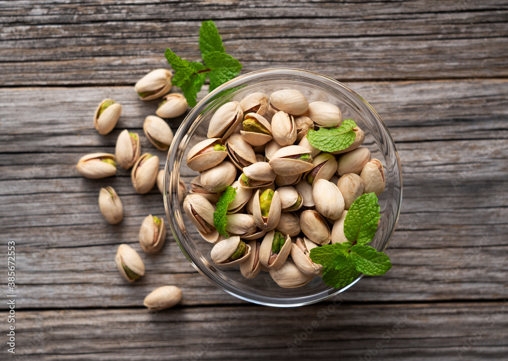 Pistachios in a bowl set against an old wooden backdrop