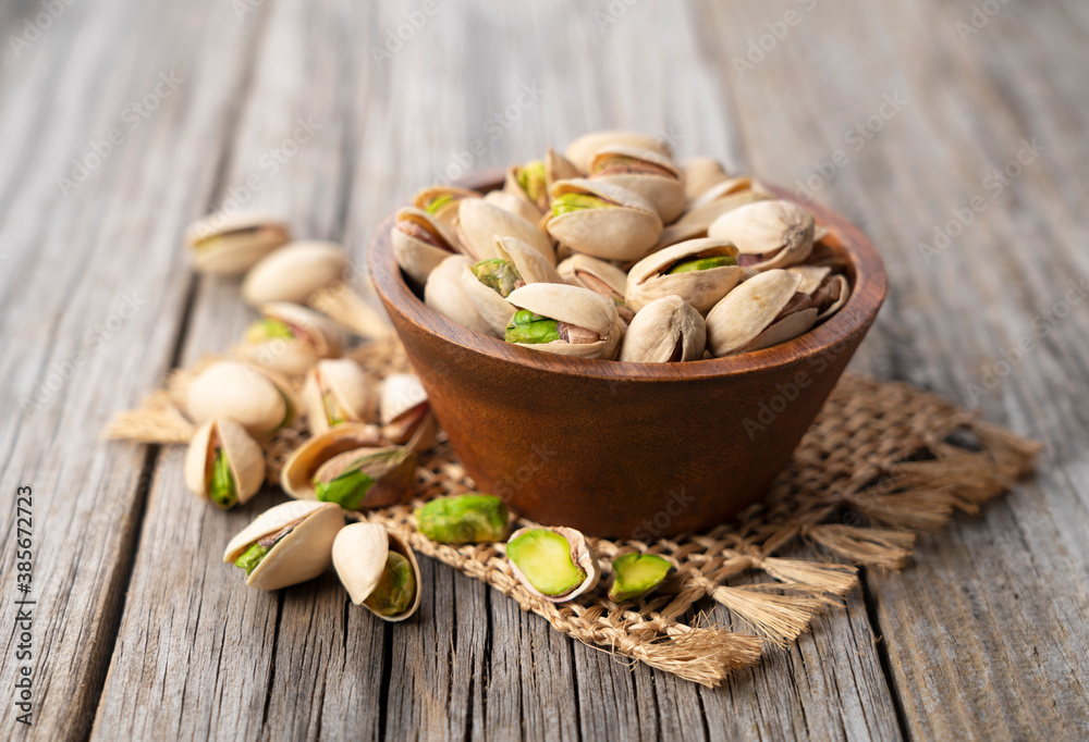 Pistachios in a bowl set against an old wooden backdrop