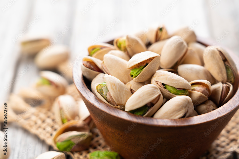 Pistachios in a bowl set against an old wooden backdrop