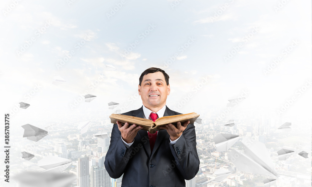 Happy businessman holding open old book