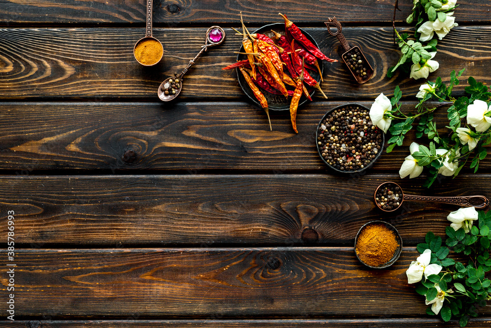 Set of spices and herbs for cooking in metal spoons and bowls, top view