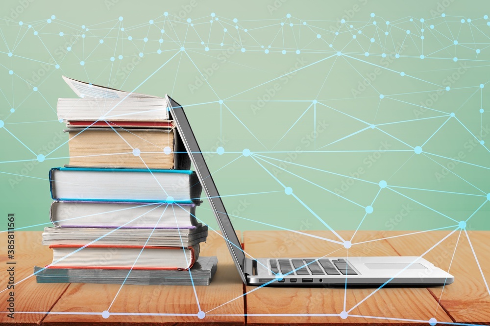 Stack of books with modern laptop on table