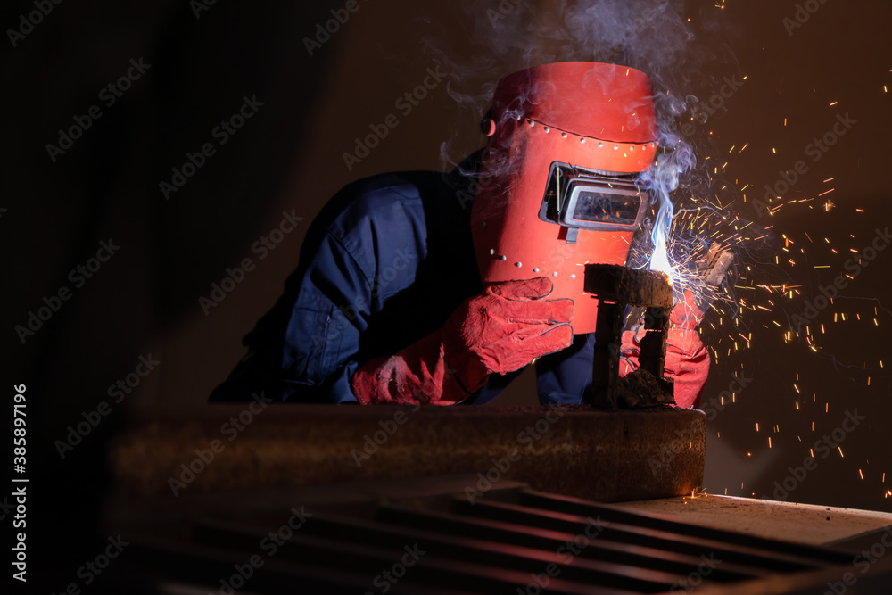 Metal welding steel works using electric arc welding machine to weld steel at factory. Metalwork man