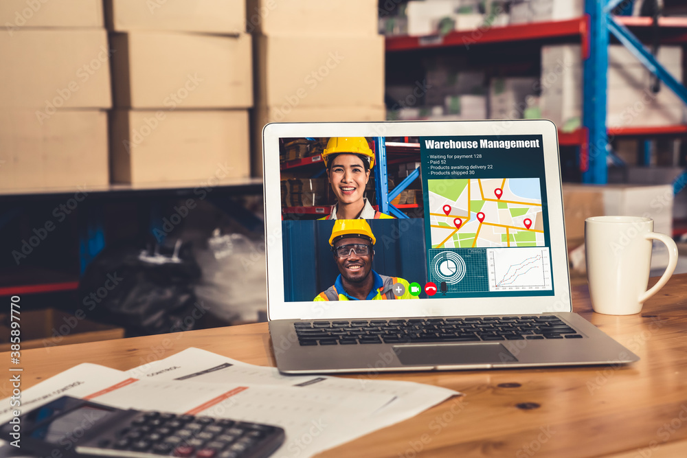 Warehouse staff talking on video call at computer screen in storage warehouse . Online software tech