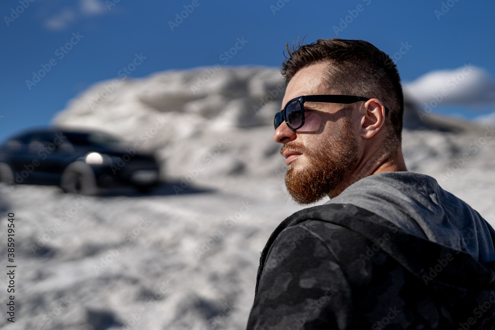 Posing for the camera. Young business man in fashion clothes outdoors. Luxury car on blurred backgro