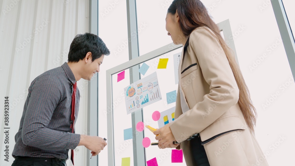 Business people work on project planning board in office and having conversation with coworker frien