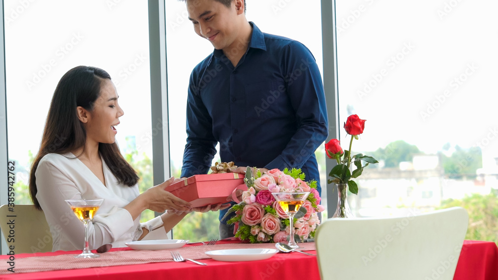 Romantic couple giving gift to lover at restaurant . Happy couple lifestyle .