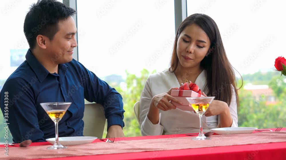 Romantic couple giving gift to lover at restaurant . Happy couple lifestyle .