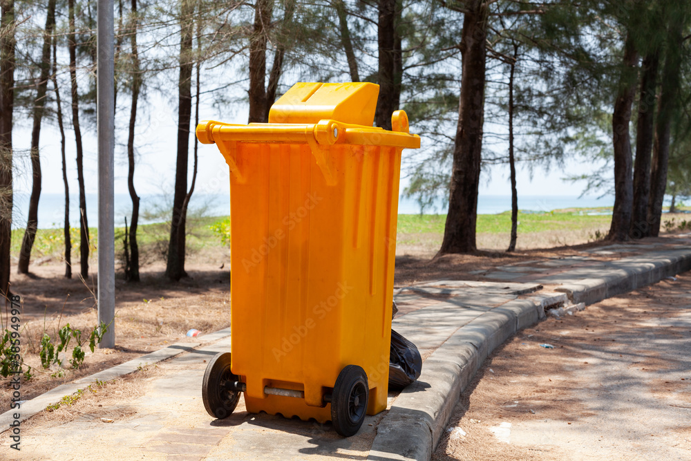 Yellow garbage bins in the park near the sea.