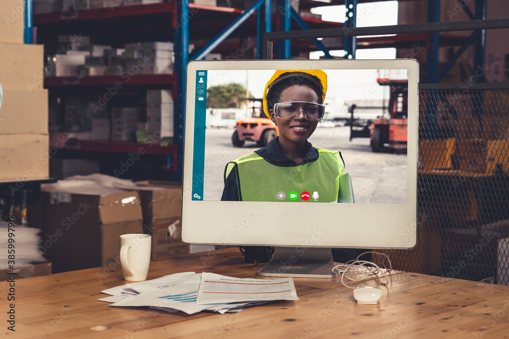 Warehouse staff talking on video call at computer screen in storage warehouse . Online software tech