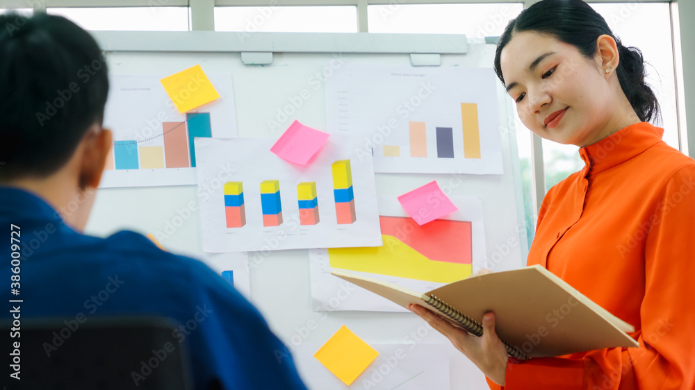 Young woman explains business data on white board in casual office room . The confident Asian busine