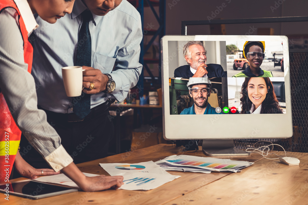 Warehouse staff talking on video call at computer screen in storage warehouse . Online software tech