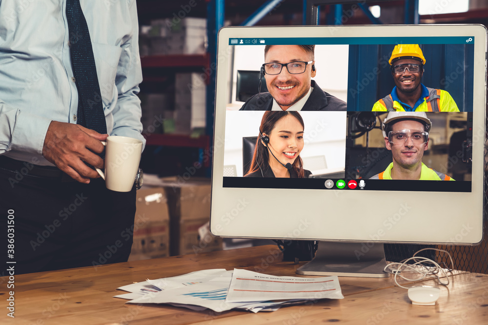 Warehouse staff talking on video call at computer screen in storage warehouse . Online software tech