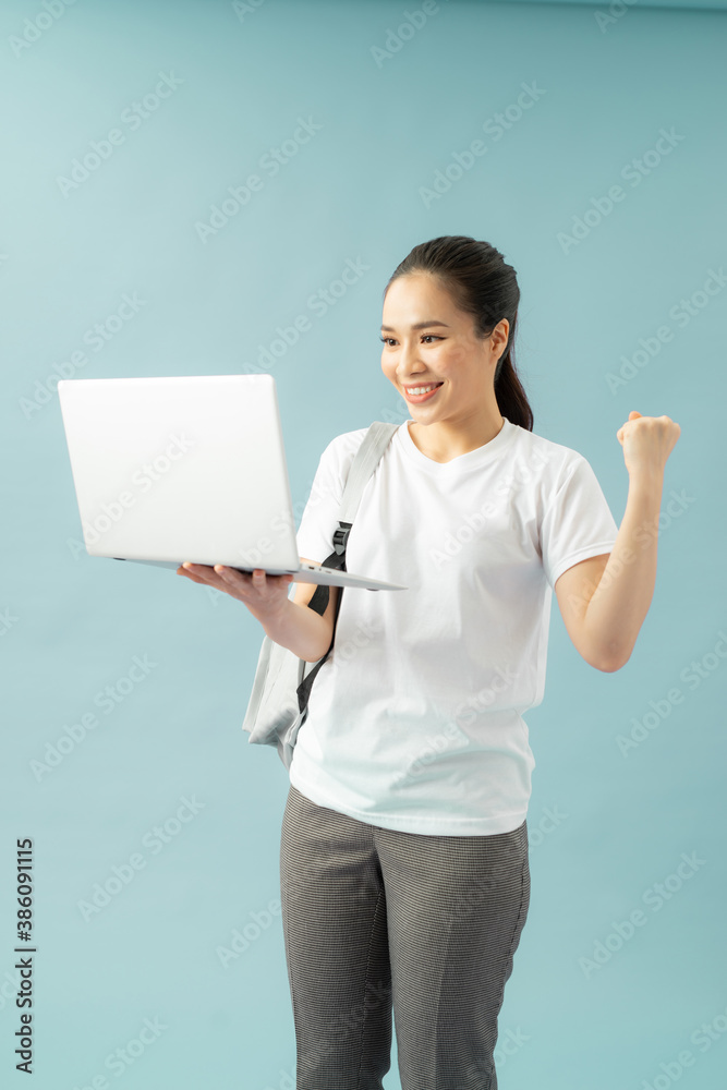 Smiling teenager with laptop on blue background