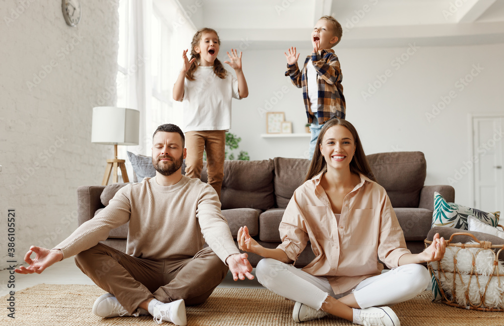 Happy parents  meditating in room with playful kids.