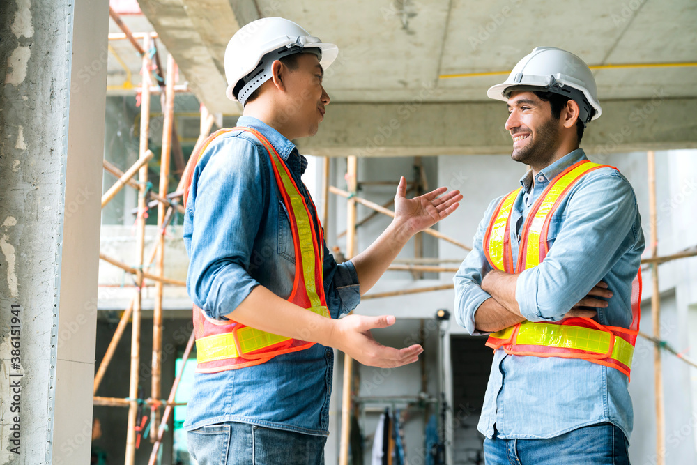 Young Asian engineers and caucasian engineer colleagues at site inspector and discuss together using