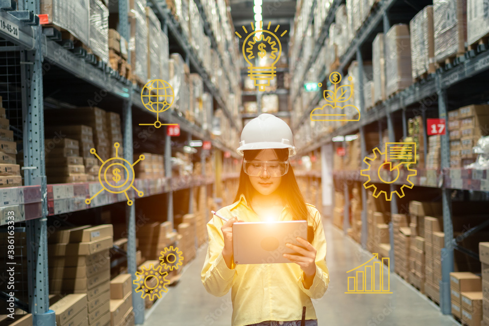 Female warehouse worker inspecting a warehouse in a factory. Wear a safety helmet and glasses for wo