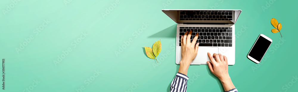 Autumn leaves with person using a laptop computer from above