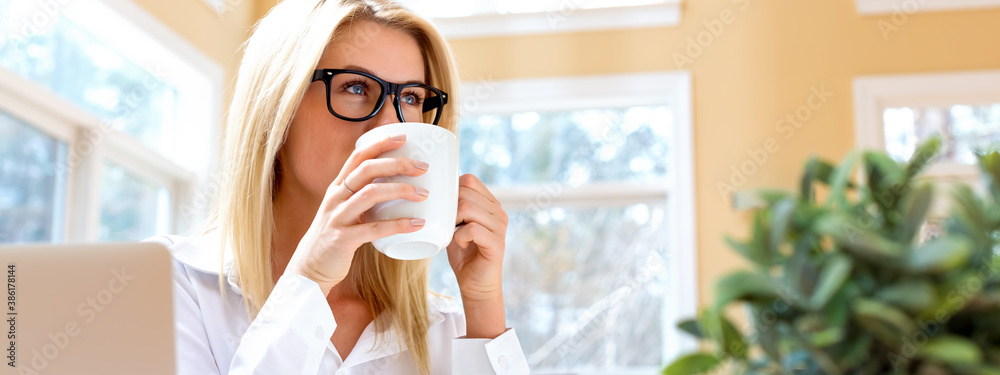 Happy young woman drinking coffee in an office