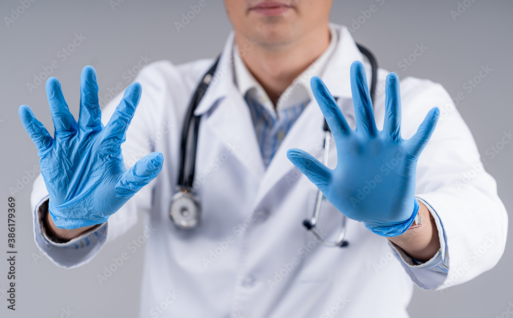 Selective focus on doctor`s hands in blue medical gloves. Cropped photo of a medic in scrubs. Health