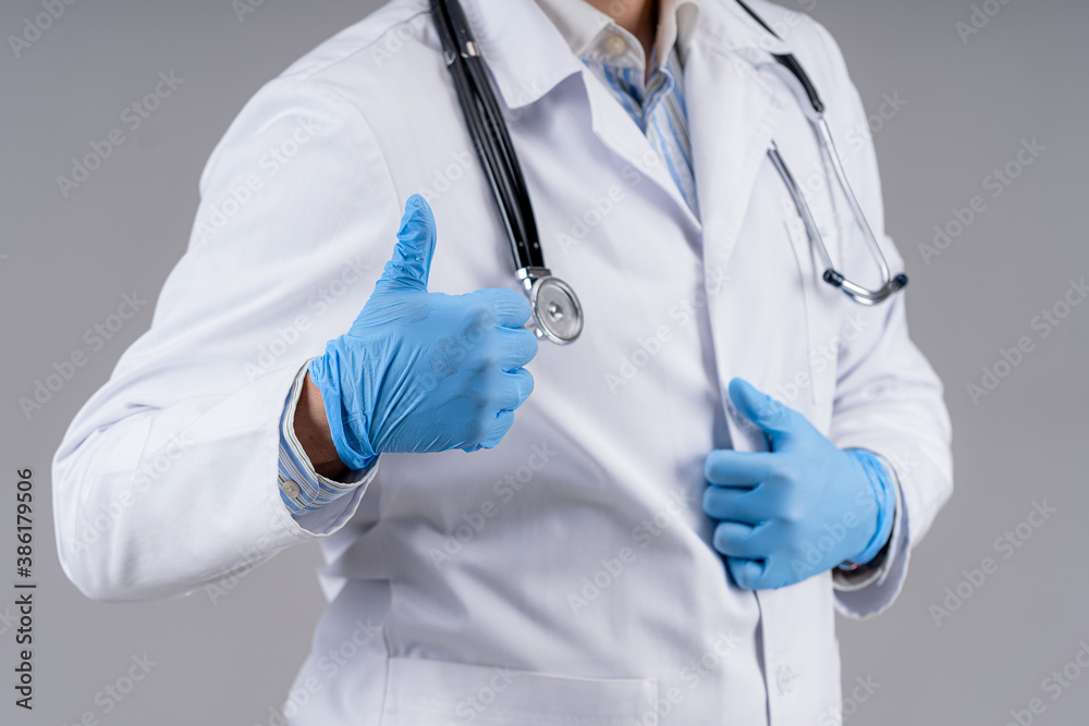 Doctor in scrubs and stethoscope showing like isolated on gray background. Selective focus. Health c