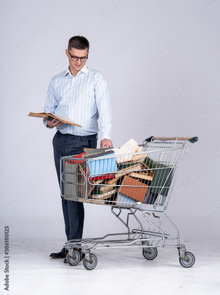 College male student studying before exam. Male student with many books in pushcart. Young man has t