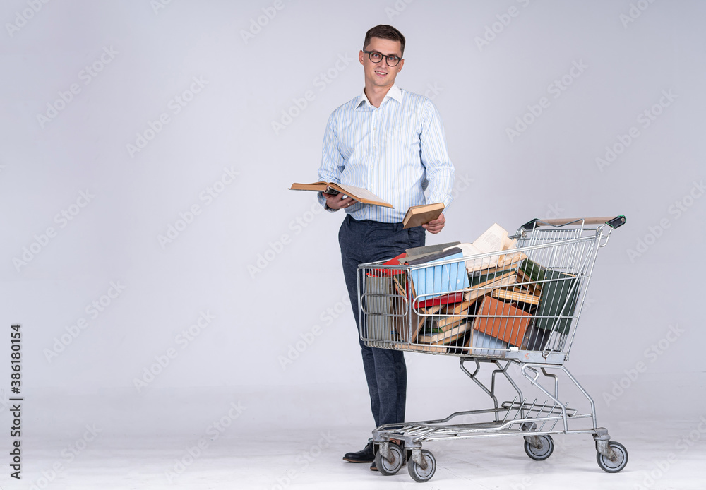 Young man in white shirt with pile of books in pushcart. Achieving results for future profession. Di