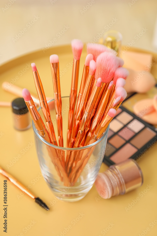 Set of makeup brushes with decorative cosmetics on table