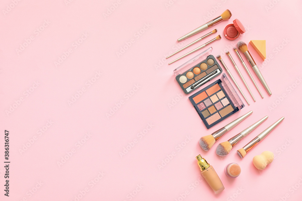 Set of makeup brushes with decorative cosmetics on color background