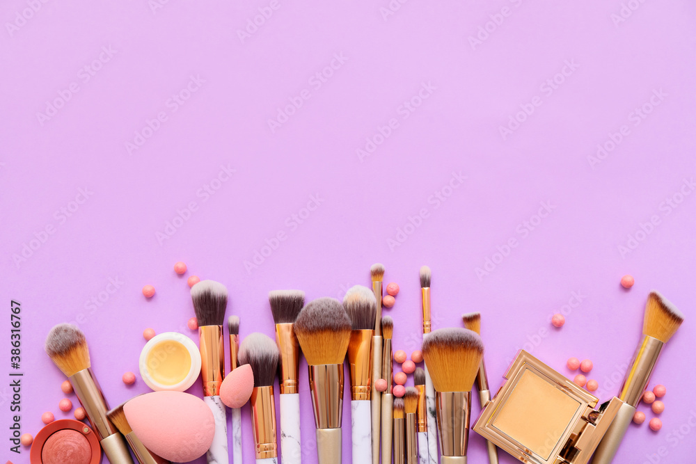 Set of makeup brushes with decorative cosmetics on color background