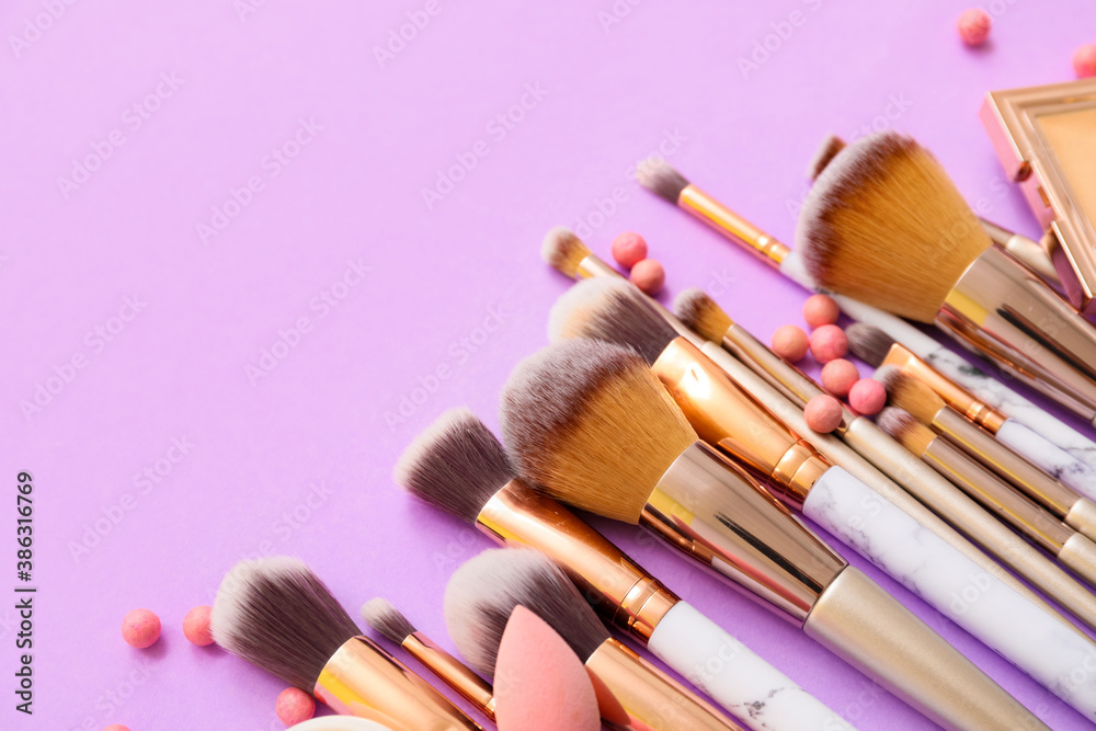 Set of makeup brushes with decorative cosmetics on color background