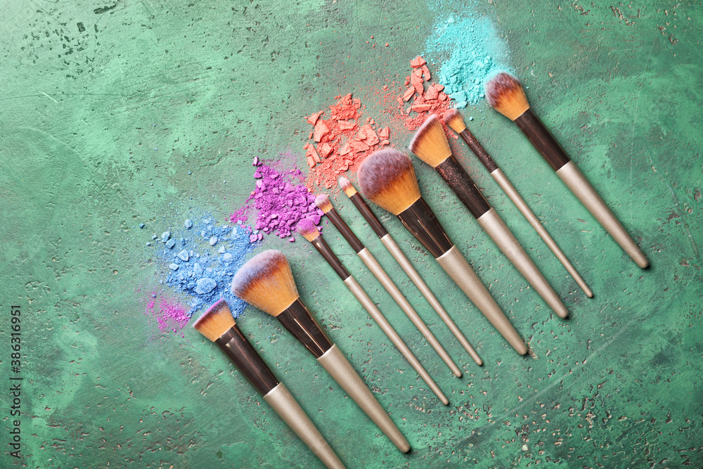 Set of makeup brushes with decorative cosmetics on color background