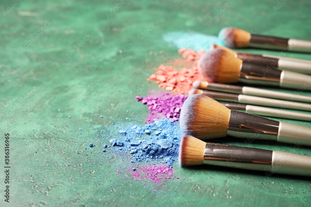 Set of makeup brushes with decorative cosmetics on color background