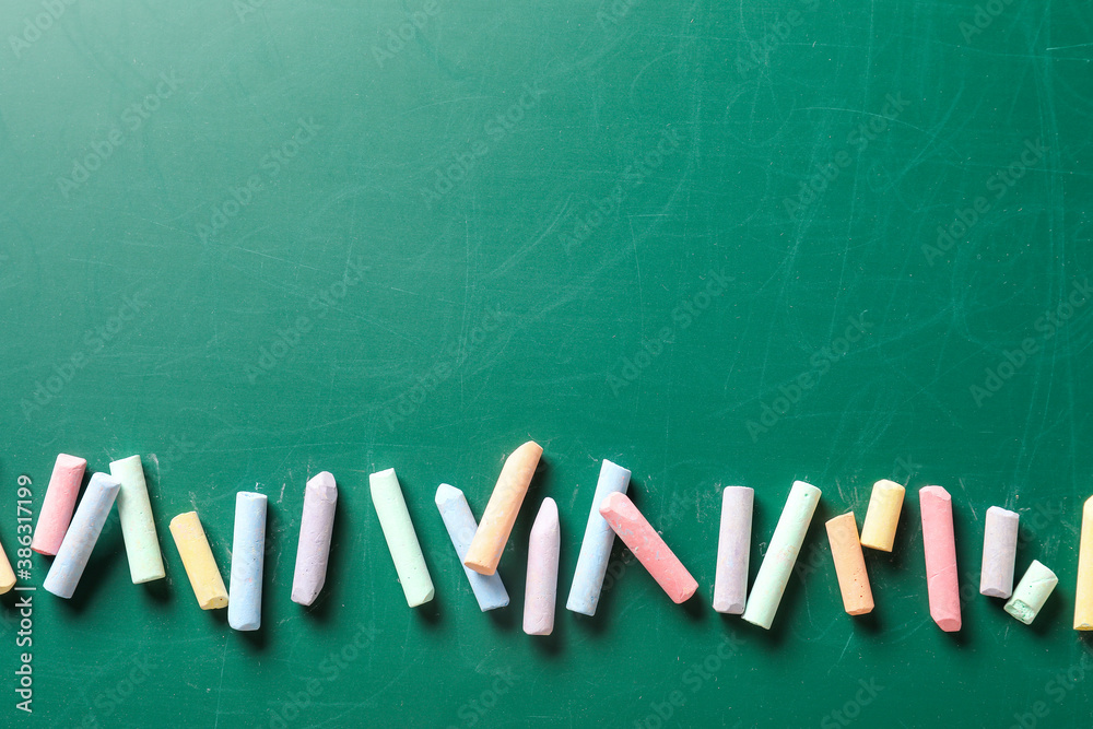 Pieces of colorful chalk on blackboard, top view