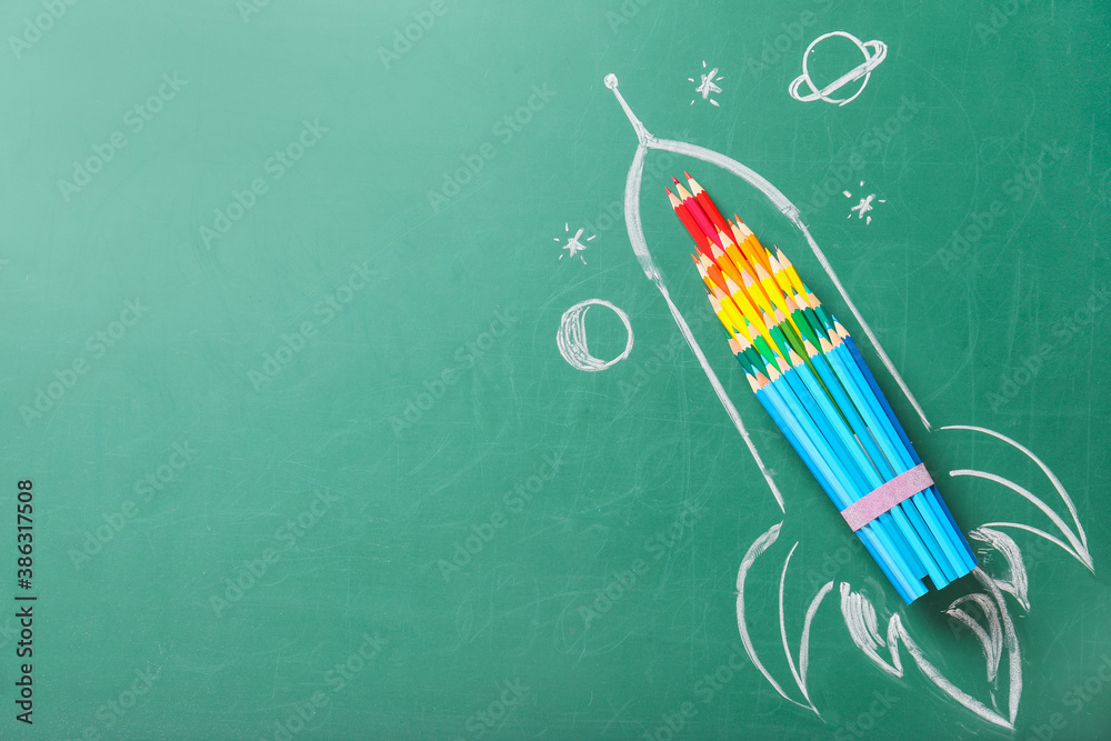 Creative composition with drawn space rocket and stationery on chalkboard