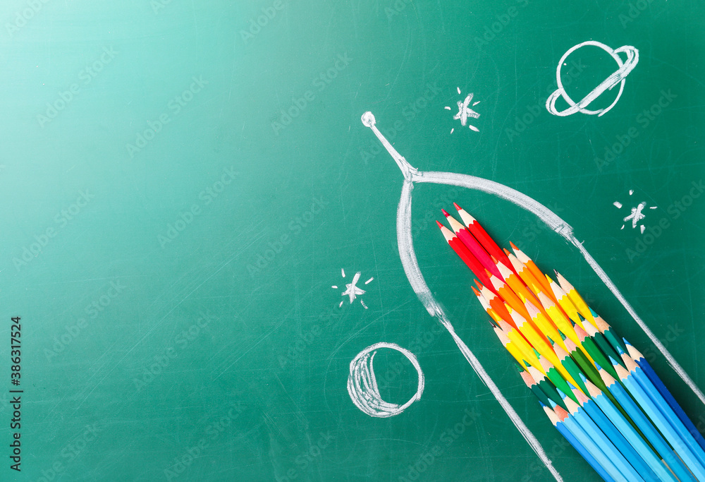 Creative composition with drawn space rocket and stationery on chalkboard