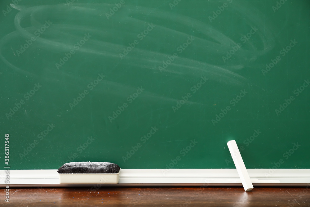 Chalk with sponge and blackboard in classroom