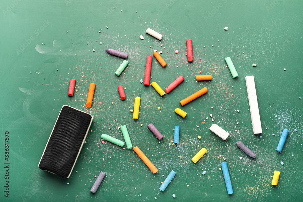 Sponge and pieces of chalk on blackboard, top view