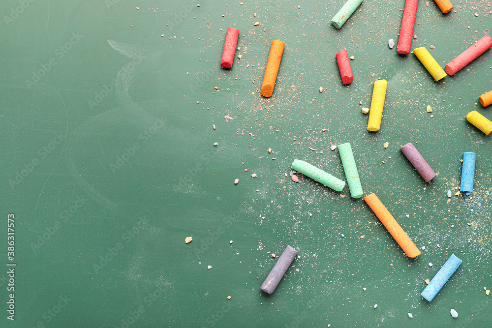 Pieces of colorful chalk on blackboard, top view