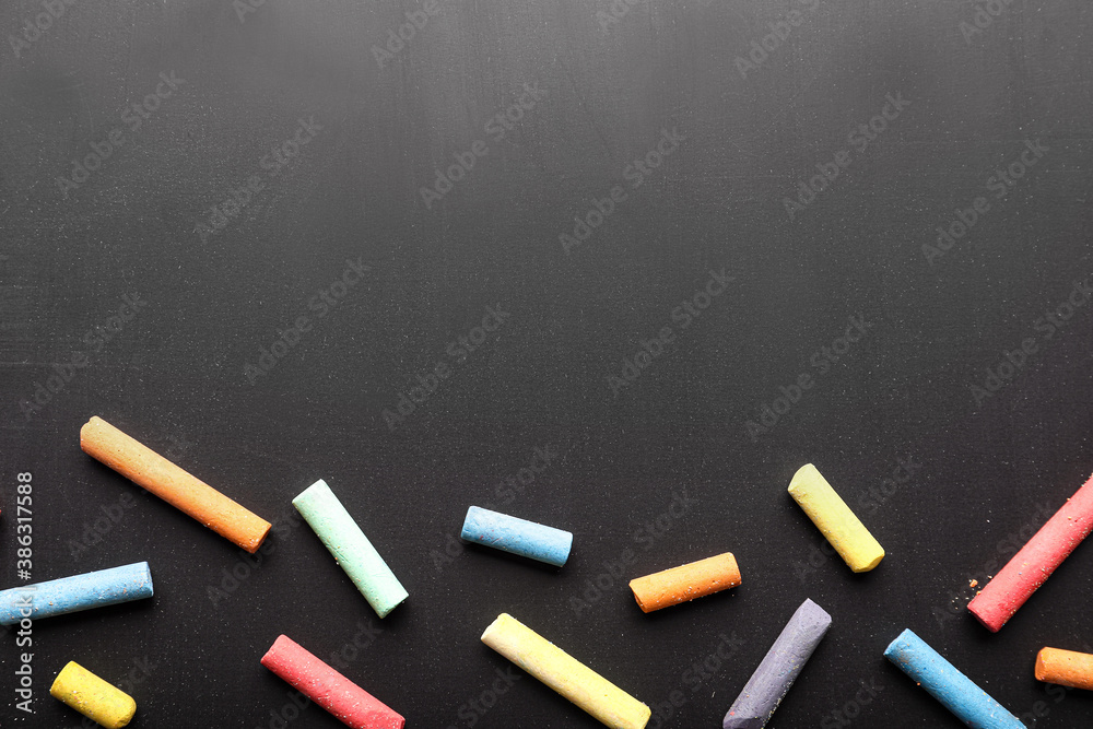 Pieces of colorful chalk on blackboard, top view