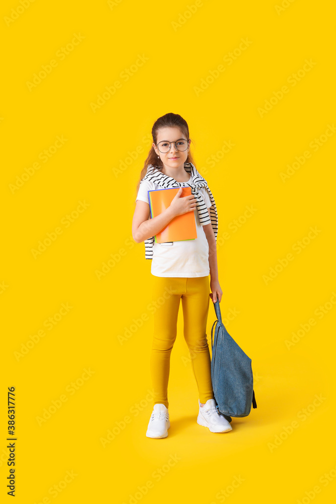 Cute little schoolgirl on color background