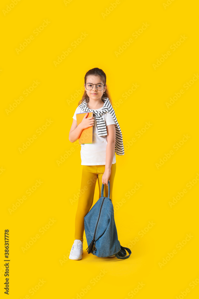 Cute little schoolgirl on color background