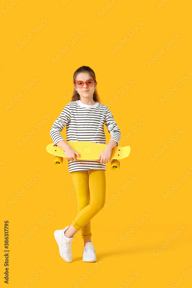 Cute little girl with skateboard on color background