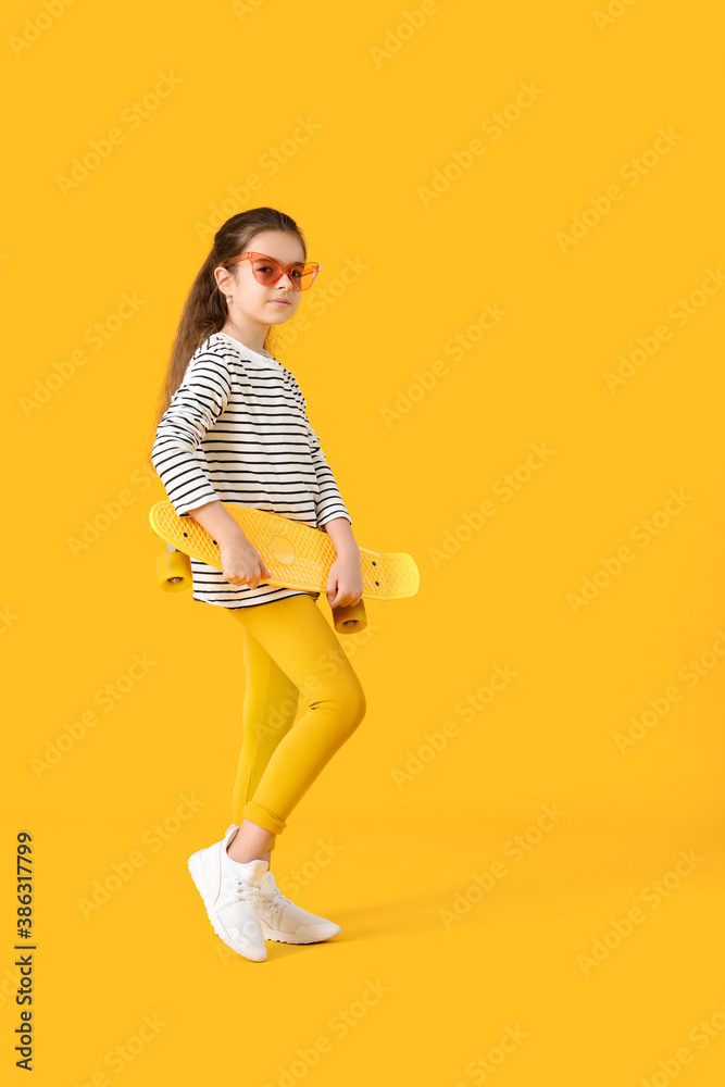 Cute little girl with skateboard on color background