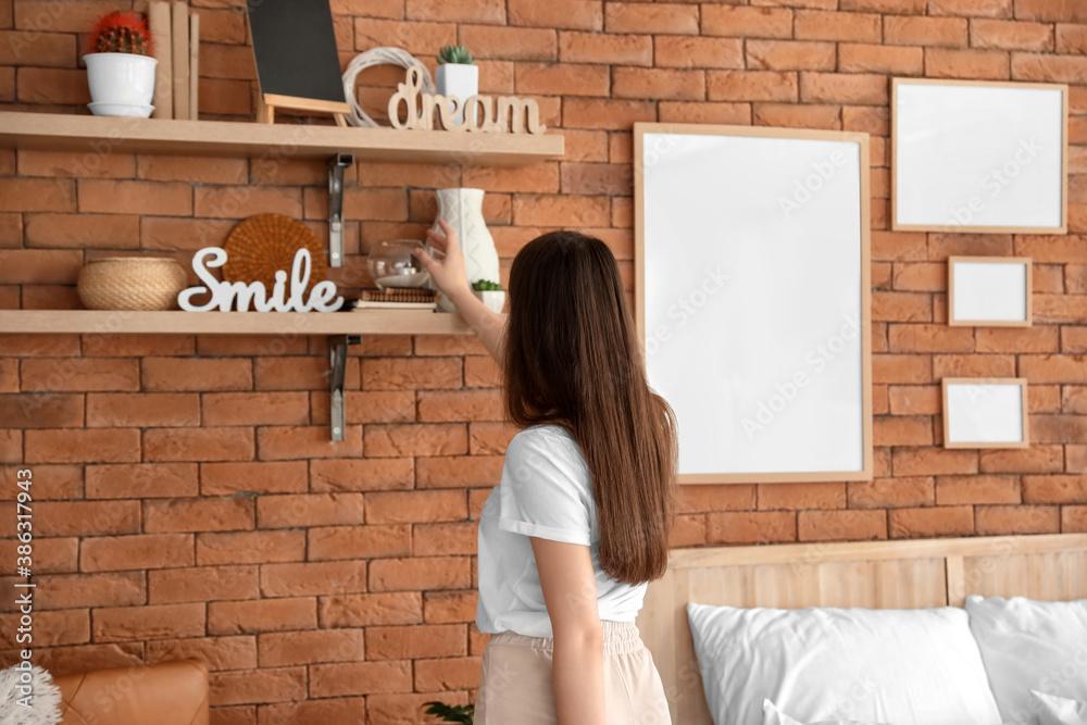 Young woman near wooden shelves in bedroom